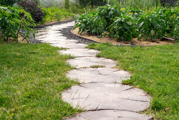 Path of plated stones on gravel bed. Garden architecture, pathway accessory to garden pond.