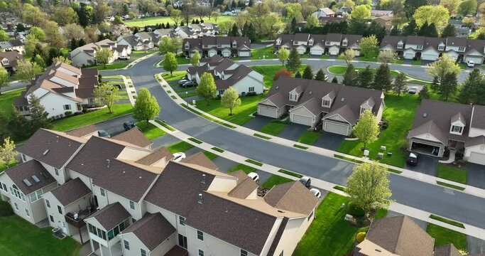 Townhouse condo apartment buildings during magic hour. Aerial drone shot above uniform tan brown houses in neighborhood community in USA. SPRING version. Autumn also available.