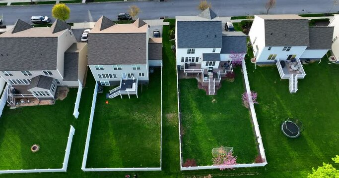 Rear exterior backyard view with white picket fence and dog yard to play in green grass for pets and children. Neighborhood aerial truck shot.