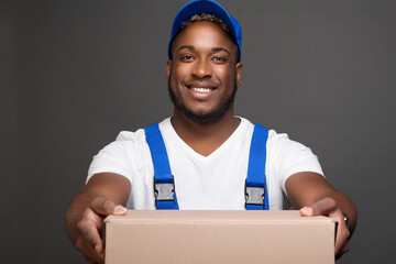 A jolly longshoreman in a blue baseball cap holds forward an empty box, transfers for packing...