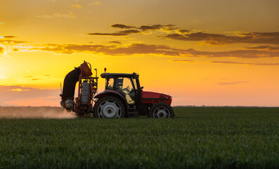 Tractor spraying pesticides wheat field.
