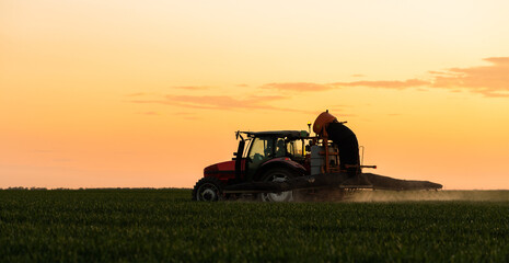 Fototapeta premium Tractor spraying pesticides wheat field.
