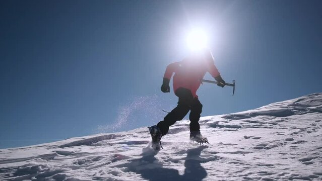 Man runs along steep snowy ridge in slow motion profile shot