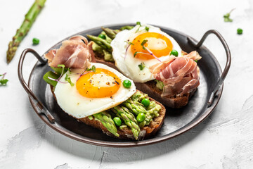 Grilled Toast witch Asparagus, Poached egg, bacon jamon, ham, banner, menu, recipe place for text, top view Food recipe background. Close up