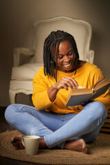 concept of leisure, literature and people - a smiling African-American woman reading a book