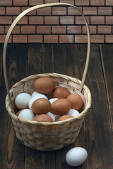 a lot of fresh chicken eggs in a straw basket on a dark wooden background. Healthy eating concept