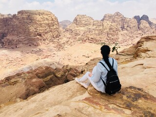 Fototapeta na wymiar Girl tourist siting on the edge of a cliff, Jordan exploring