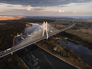 a large white suspension bridge over the river on which cars drive in Wroclaw, Poland, shot from a drone