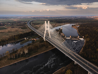a large white suspension bridge over the river on which cars drive in Wroclaw, Poland, shot from a...