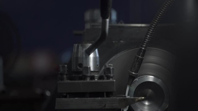 Turning bench lathe machine working on a metal rod piece casting metal shavings - closeup on the cutting edge and workpiece