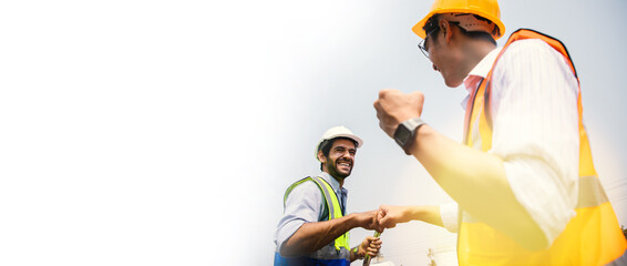 Engineers working on train garage site and holding hands to fist bump after success project with sunny. Portrait of positive thinking of engineering teamwork. Happiness and successful jobs concept