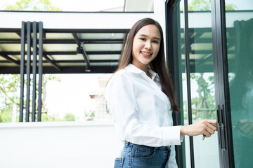 Asian business woman use key for lock or unlock glass door at house projects. Concept of real estate agent or receiving house for rent