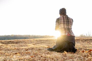 Woman kneeling in sunshine on brown hill