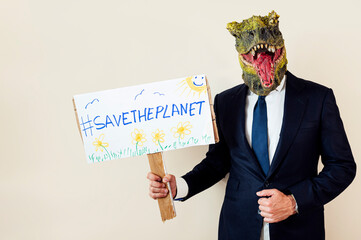 Man with a lizard head in studio WITH cardboard sign that says #SAVETHEPLANET