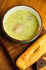 Peas soup in the yellow bowl on the wooden background.