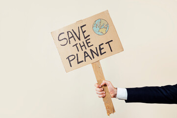 Man's hand holding a cardboard sign that says SAVE THE PLANET