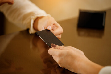 Receptionist girl with visit card in hands. Close up. The hostess at the reception holds a business...