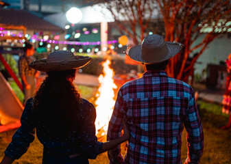 Casal em frente a uma iluminada fogueira de festa junina