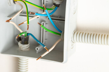 Bare contacts of electrical wires in a junction box on the wall