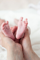 Obraz na płótnie Canvas Tiny newborn baby feet on female hands closeup