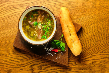 Georgian soup in a plate with damashna bread on a wooden board