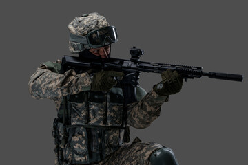 Shot of serviceman dressed in protective helmet and uniform aiming rifle.