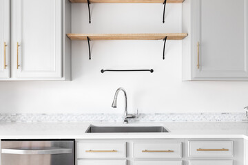 A modern farmhouse kitchen detail shot with grey cabinets, marble countertop and tiled backsplash,...