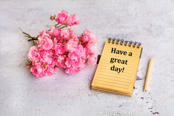 Notebook with have a great day message and bouquet of roses flowers 