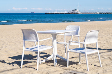 Fototapeta na wymiar White chairs and table on the sandy beach