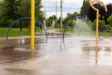 Splash pad playground on a sunny summer day. Park with splashing water fountains.