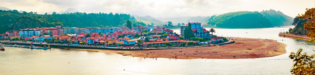 Paseo marítimo en el pueblo pesquero de Ribadesella, Asturias, España. Paisaje escénico de arquitectura y playa,puerto con barcos y casas.