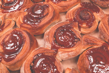 Homemade cinnamon buns with spices and caramel on parchment paper.