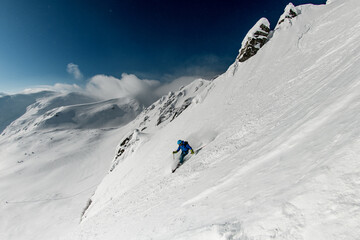 Male freerider skis sideways down on snowy mountain slope