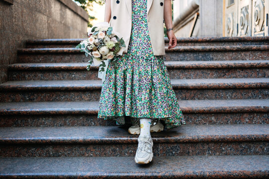 Contemporary modern trendy Hipster bride in informal dress and sneakers with Edible Wedding Bridal Flower Bouquet. Modern gen z Bride leg in comfortable shoe sneakers