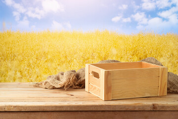 Empty wooden box on table over beautiful wheat field background.  Jewish holiday Shavuot mock up...