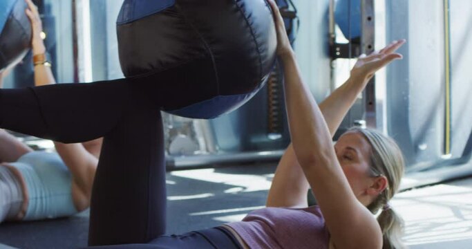 Young woman performs abdominal workout with medicine ball�