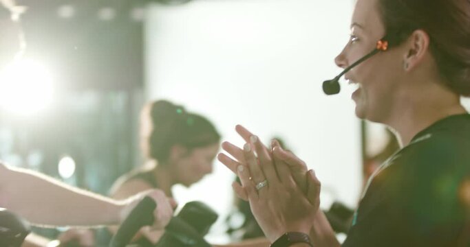 Encouraging fitness coach instructs a spin class with microphone headset
