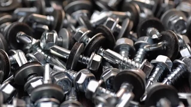 Roofing screws are lying on the table close-up. Smooth passage of the slider over the screws.
