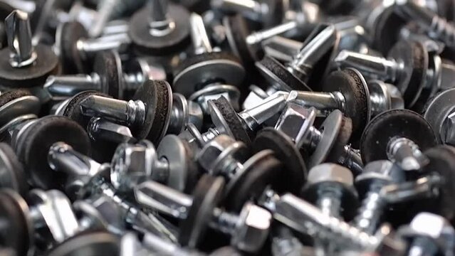 Roofing screws are lying on the table close-up. Smooth passage of the slider over the screws.