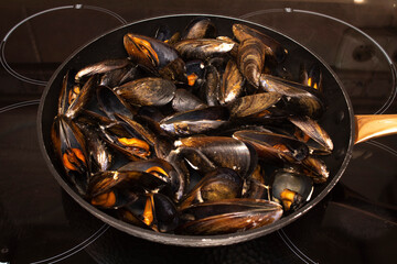 Cooking mussels in a pan. Mussels are perfect in endless fish recipes, but the simplest and most traditional in Galicia are steamed mussels.