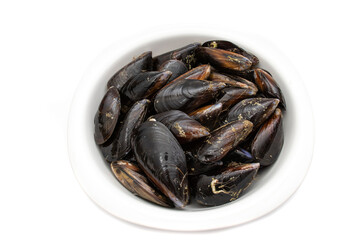 Raw mussels in a white bowl, isolated on white background. It feeds on phytoplankton and zooplankton, and even decomposing organic particles found in seawater, by filtering it through its gills.