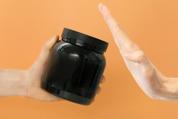 Man refusing a black protein jar supplement bottle on a yellow background. Mockup. Blank. Empty....