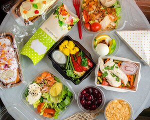 Fototapeta na wymiar Ready food catering menu in lunch boxes as daily meal diet plan courier delivery with fork on white table background. Top view. Meat with vegetables, desserts, pie and a sandwich.