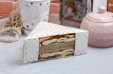 Ham sandwich in a cardboard box with a transparent window. Snack for delivery