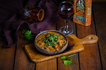 Georgian veal chashushuli with tomatoes and greens on a wooden background