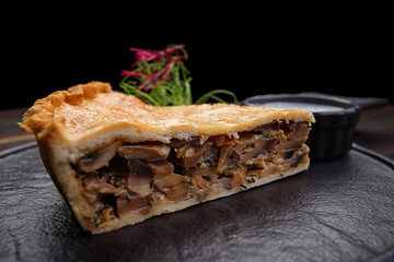 Piece of baked pie with mushrooms and sauce