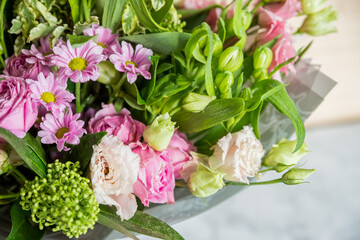 big bouquet of roses, daisies, lisianthus, chrysanthemums, unopened buds on a white table. bouquet for Woman's Day, mother's day or Valentine's Day.