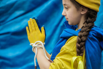 girl with a braid in a yellow sweater on a blue background with tied hands painted in blue and...