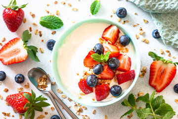 Greek Yogurt with granola and fresh berry mix at white stone table. Top view image.