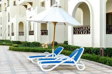 Beach chair, chaise longue near swimming pool on hotel resort backyard on warm sunny day outdoor....